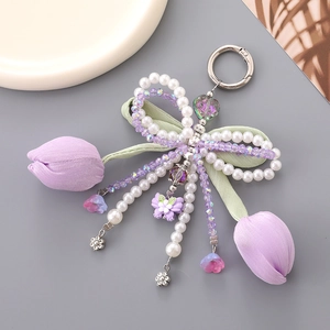 Close-up of purple fabric tulip keychain with white pearls and a butterfly charm