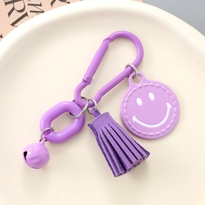 Detail of purple keychain with smile face charm, suede tassel, bell and D-ring buckle