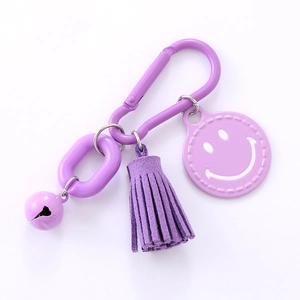 Purple tassel keychain with smiley face pendant and bell on a white background