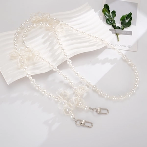 Detail of white pearl crossbody strap with four hand-woven crystal 3D bow accents
