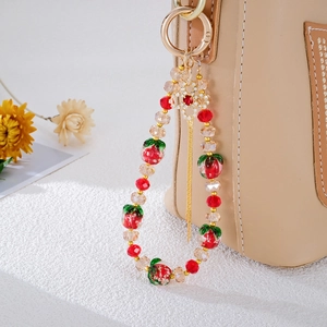 Detail of strawberry bag charm with red glass beads and sparkling crystal tassel on a bag
