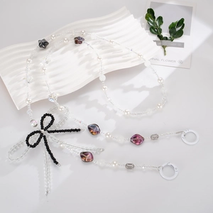 Close-up of beaded phone strap with white pearls and a black woven crystal bow charm