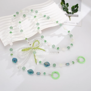 Detail of beaded mobile strap featuring green crystal bow and blue geometric acrylic beads