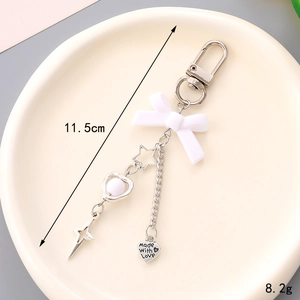 Porte-clés avec nœud blanc, charms cœur et étoile sur une assiette en céramique