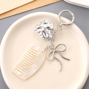 Detail view of heart charm and acrylic mini comb keychain on a ceramic plate