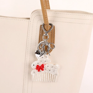 Acetate rabbit hair comb bag charm with a red bow and rhinestones on leather tote