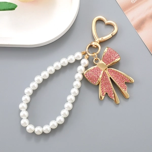 Porte-clés avec nœud en strass rose, chaîne en perles blanches et fermoir cœur
