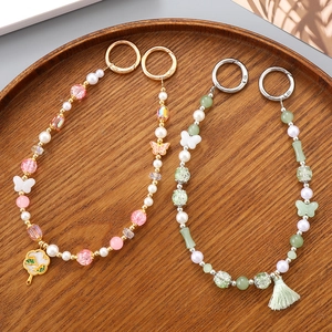 Handmade beaded fan pendant keychain with butterfly and floral charms in a wooden tray