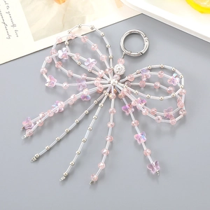 Pink and silver beaded bow phone charm with fringe tassels on minimalist background