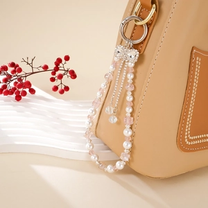 Elegant pearl and pink crystal bag charm with a rhinestone bow and spring ring buckle