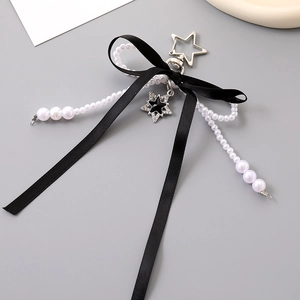 Close-up of black satin bow keychain with white pearls and a star pendant accessory