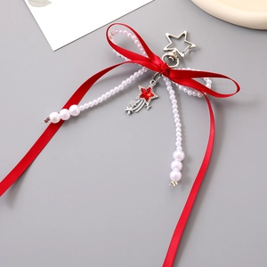 Detail of red ribbon bow keychain with pearls and a star-shaped crystal meteor charm