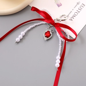 Detailed close-up of a red bow keychain with white pearls and a teardrop ruby pendant