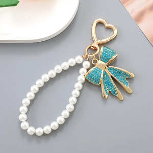 Dettaglio portachiavi con fiocco di strass blu, catena di perle e chiusura a cuore