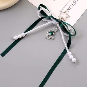 Detail of dark green ribbon bow keychain with silver fox pendant and white pearls
