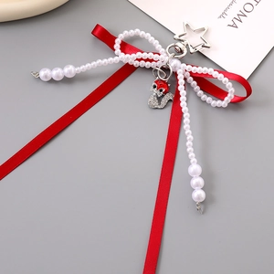 Detail of red silk ribbon bow with pearl bead bow and silver star-shaped metal clasp