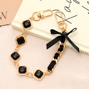 Crossbody phone chain with black ribbon bow and diamond-shaped gemstone accents