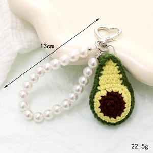 Detailed view of handmade crochet avocado keychain with white pearl bead strap and heart clasp