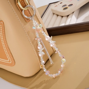 Detail of luxury beaded butterfly keychain with pink pearls on a beige leather bag