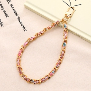 Dettaglio della catena in metallo dorato intrecciato con tessuto tweed e chiusura a moschettone