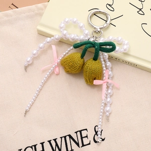 Close-up of pearl bow and knitted tulip charm on a canvas bag for a stylish aesthetic