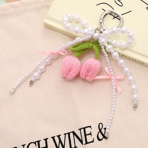 Close-up of handmade crochet pink tulip charm with white pearl bow and silver clasp