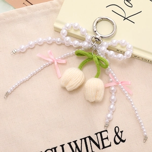 Close-up of handmade knit tulip bag charm with faux pearls and silk bow detail