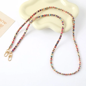 Detail of woven gold metal chain strap with colorful fabric ribbon for bags or phones