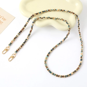 Detail of colorful woven fabric and gold chain strap with lobster clasps on tray