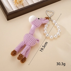 Makroaufnahme der lila Strick-Giraffe mit Perlenarmband und Metall-Herzverschluss