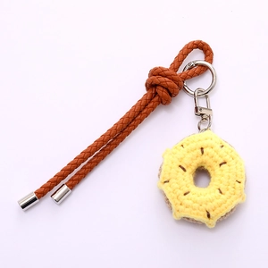 Handmade crochet donut bag charm with dark brown woven leather strap and silver metal clasp