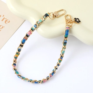 Detail of woven fabric and metal chain strap with a camellia pendant and gold lobster clasps