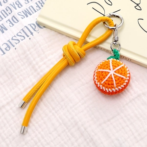 Handmade crochet orange fruit charm with yellow leather strap on minimalist background