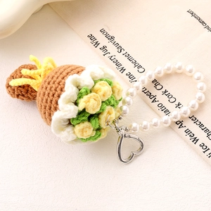 Macro detail of a handmade crochet flower bouquet phone charm with pearl wrist strap