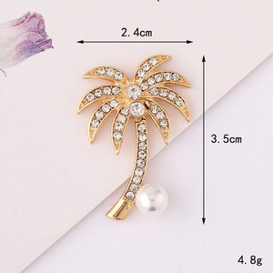 Detailed view of a gold palm tree brooch with sparkling rhinestones and a white pearl accent