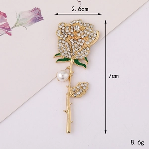 Detail view of rose brooch with white rhinestones, green enamel leaf, and white pearl