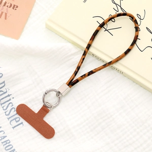 Detail of leopard print phone strap with brown fabric patch and silver metal ring on books
