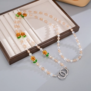 Detailed macro of a beaded crossbody chain with glass flowers and metal spring rings