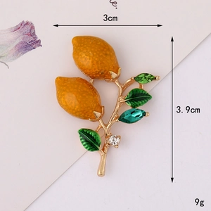 Detail view of lemon brooch with yellow texture, green leaves and crystal gems, 3x3.9cm