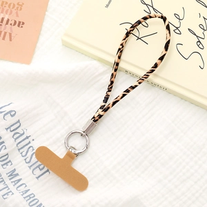 Detail of leopard print phone lanyard with metal ring and brown connector pad on soft fabric