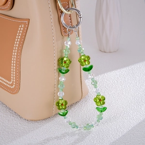 Exquisite green beaded flower phone charm attached to a brown leather bag accessory