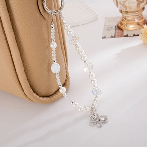 Detail of beaded phone strap with iridescent petals and silver bow on leather bag