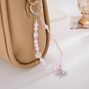 Detail of beaded phone strap with pink butterfly pendant on a leather handbag