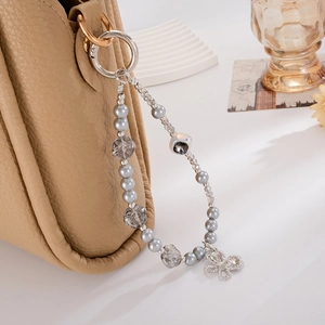 Close-up of a silver butterfly charm with grey pearls on a luxury leather handbag