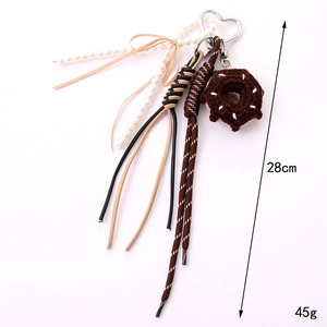 Handmade woven donut phone charm with white pearls and pink ribbon bow on white background