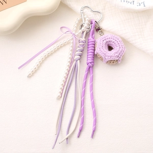 Macro detail of handmade lavender crochet donut phone charm with pearls and purple bow