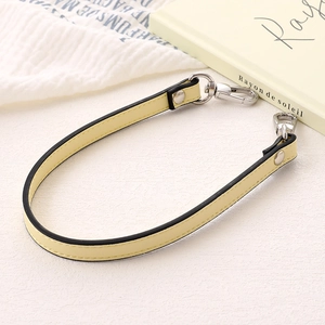 Close-up of pale yellow PU leather phone strap with silver lobster clasps on white background