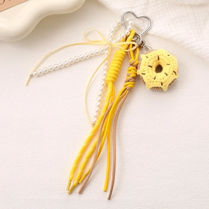 Close-up of handmade crochet donut charm with pearl chain and yellow silk bow tie