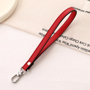 Detail of red lychee grain leather wrist strap with silver metal spring buckle and rivet