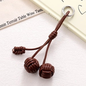 Detailed macro view of reddish-brown braided PU leather phone charm with metallic ring